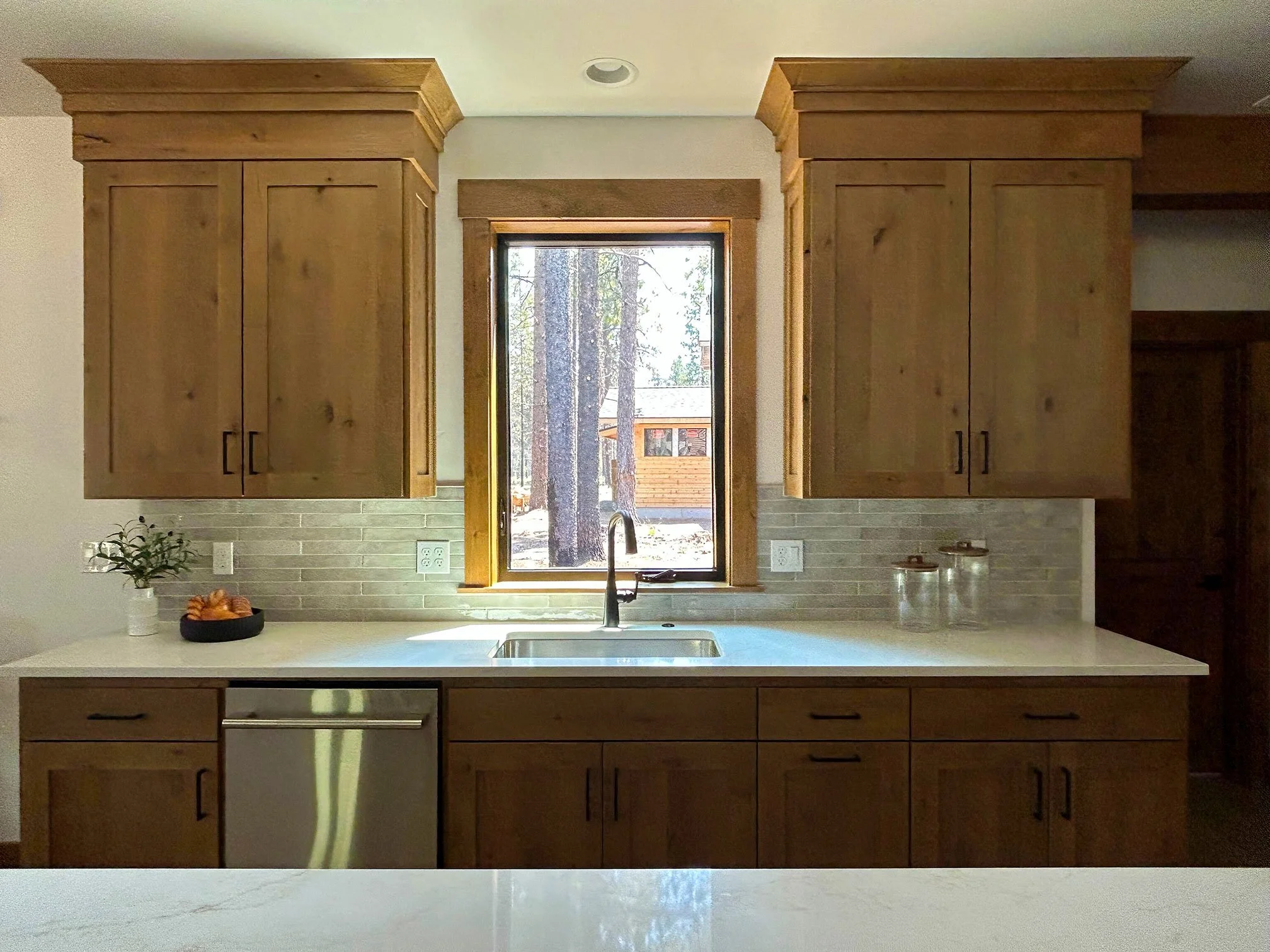 Modern kitchen with wooden cabinets, a window above the sink, and a stone tile backsplash in Bend, Oregon.