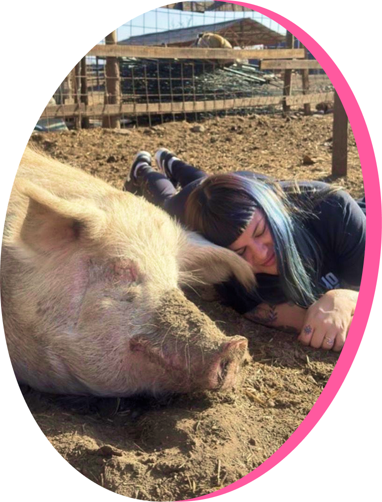 Person smiling and laying with pig
