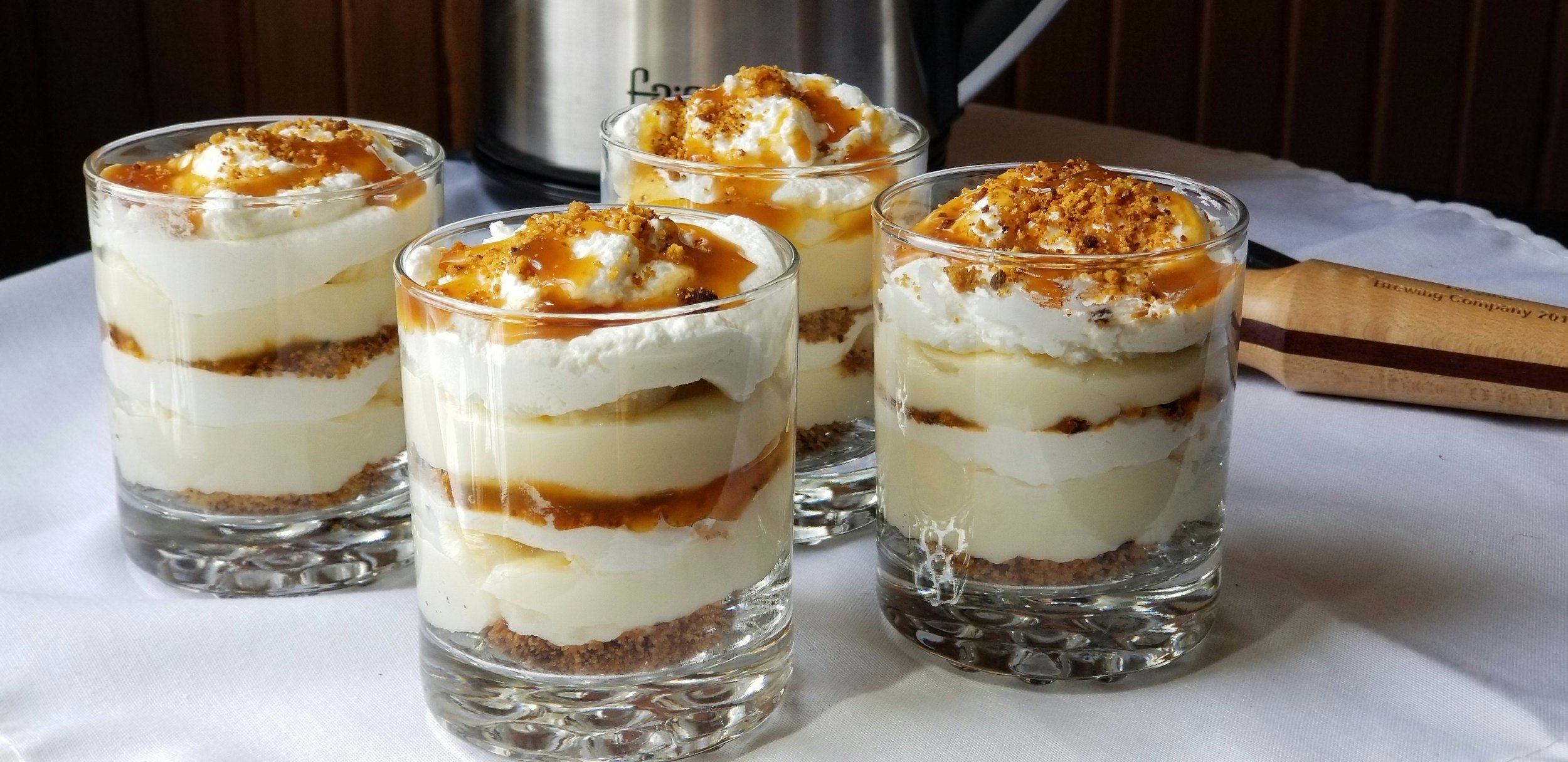 Three parfaits with custard, whipped cream, and banana bread latte syrup
