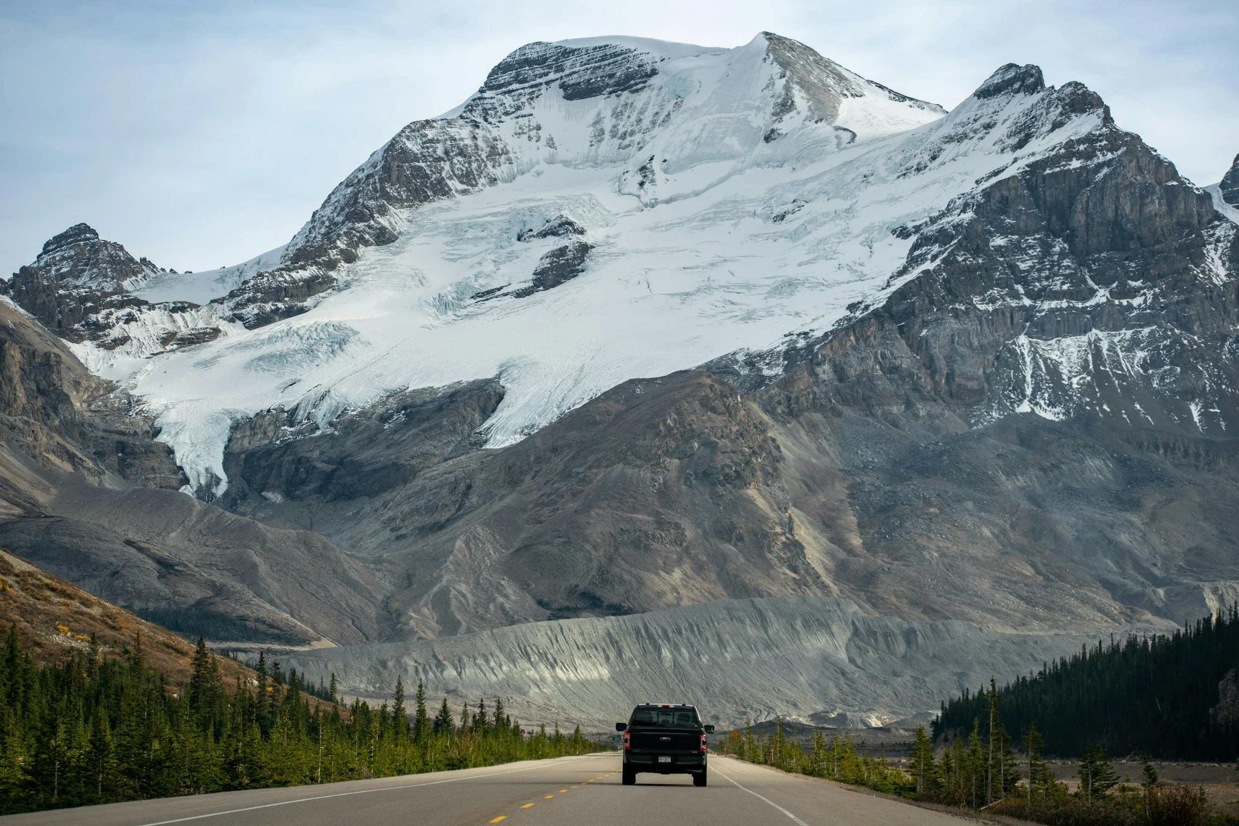 Black truck driving down an Alberta road towards a mountain