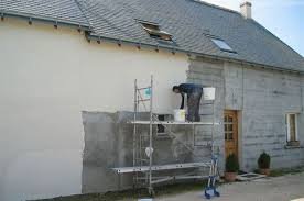 Personne effectuant des travaux de rénovation sur la façade d'une maison, utilisant un échafaudage.