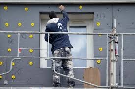 Travailleur sur échafaudage isolant une façade.