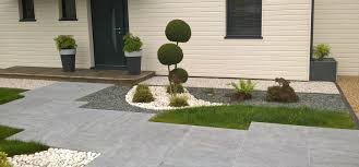 Aménagement de jardin moderne avec plantation de buis taillé, allée en pierre et parterre de gravier devant une maison.
