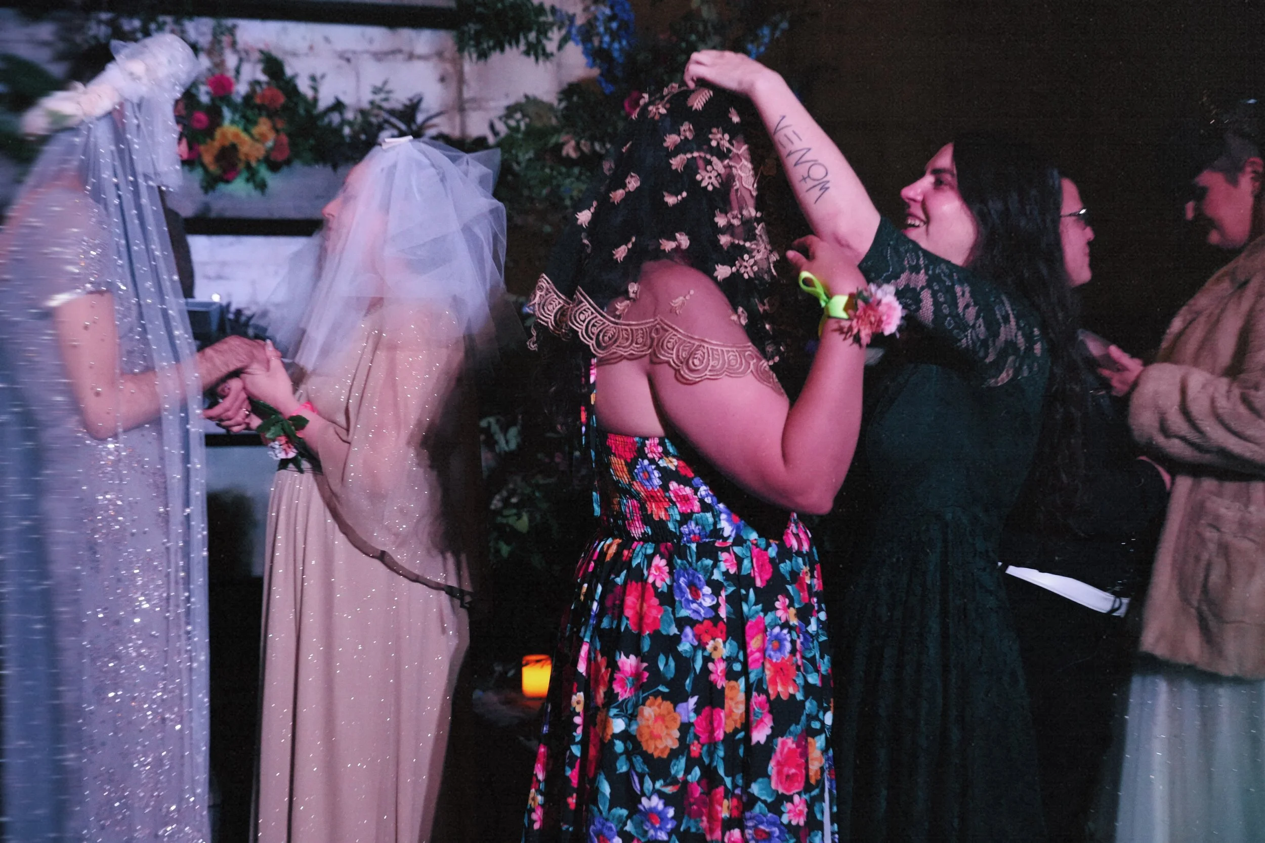 Group of women celebrating at a wedding reception, with the bride wearing a veil, and two women dancing happily.