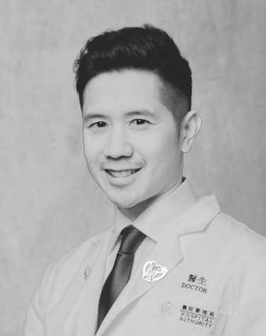 Black-and-white photograph of a young male doctor wearing a white coat with a name tag and hospital authority badge, smiling at the camera.