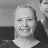 Black and white photo of a smiling woman with light-colored hair pulled back.