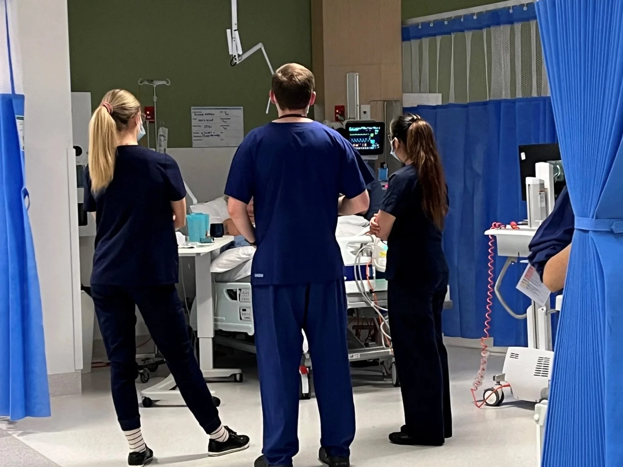 Healthcare professionals in blue scrubs with patient on bed