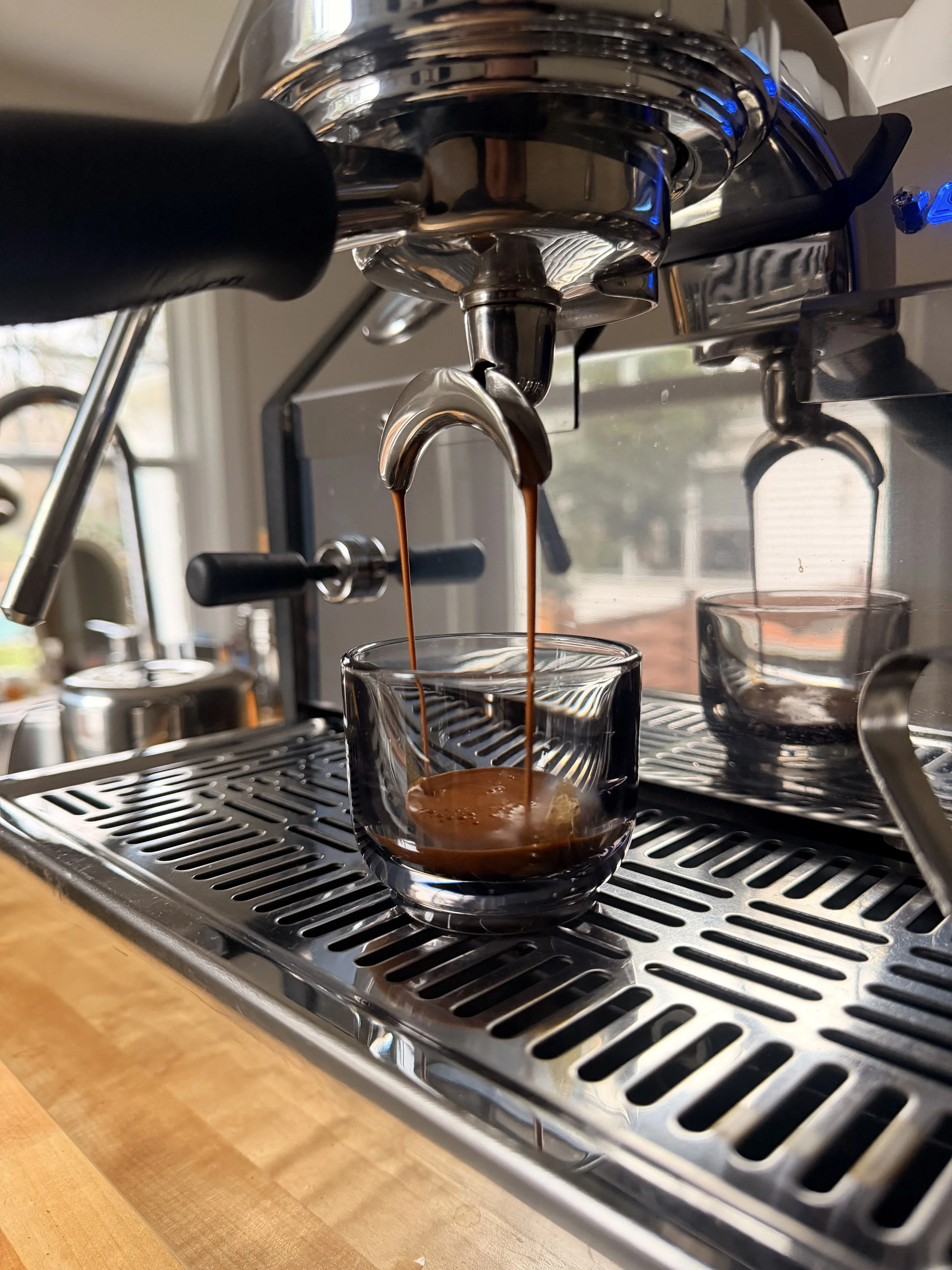 Close-up of a coffee espresso machine pouring dark espresso into a glass cup.