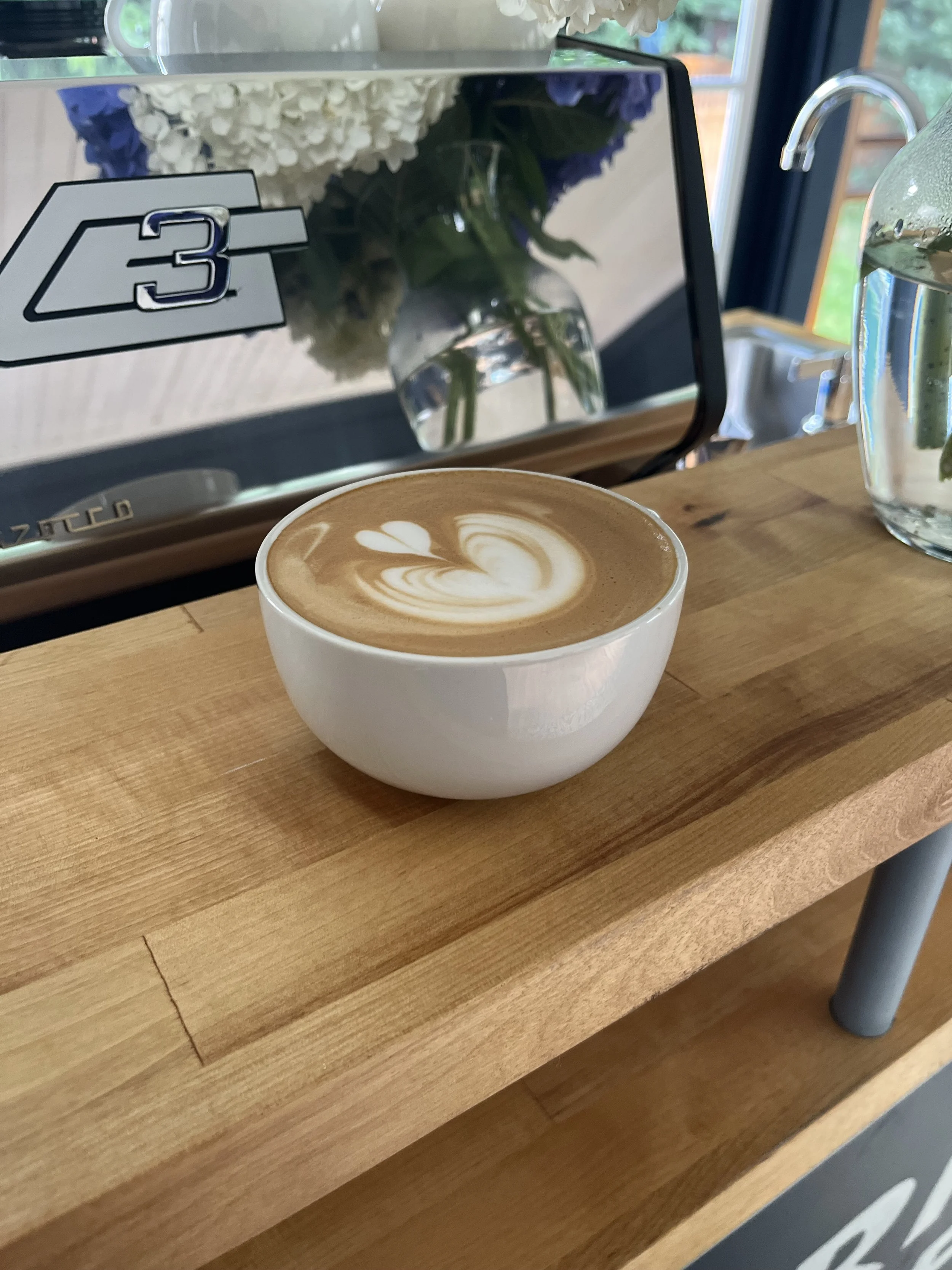 A cup of latte with latte art on a wooden table in a cafe.