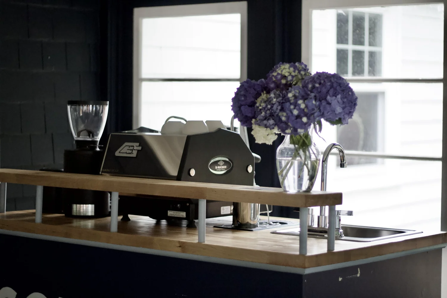 Solarium Coffee espresso setup in natural light beside a vase of purple and white hydrangeas