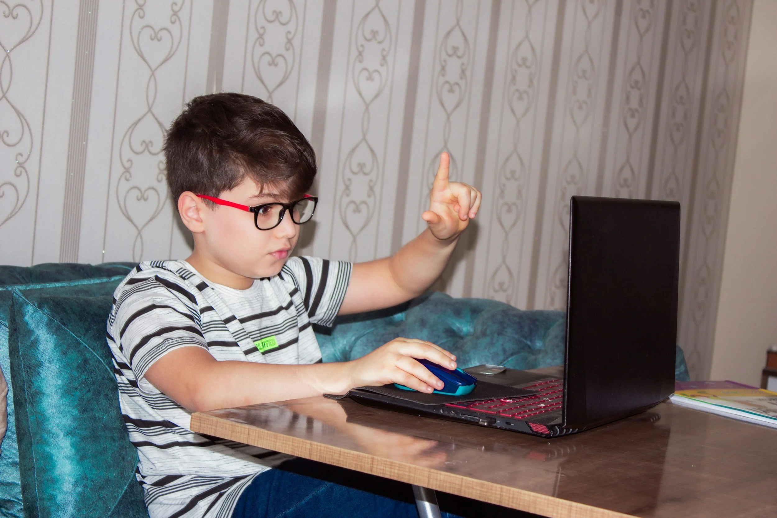 Boy sitting at computer talking to teacher
