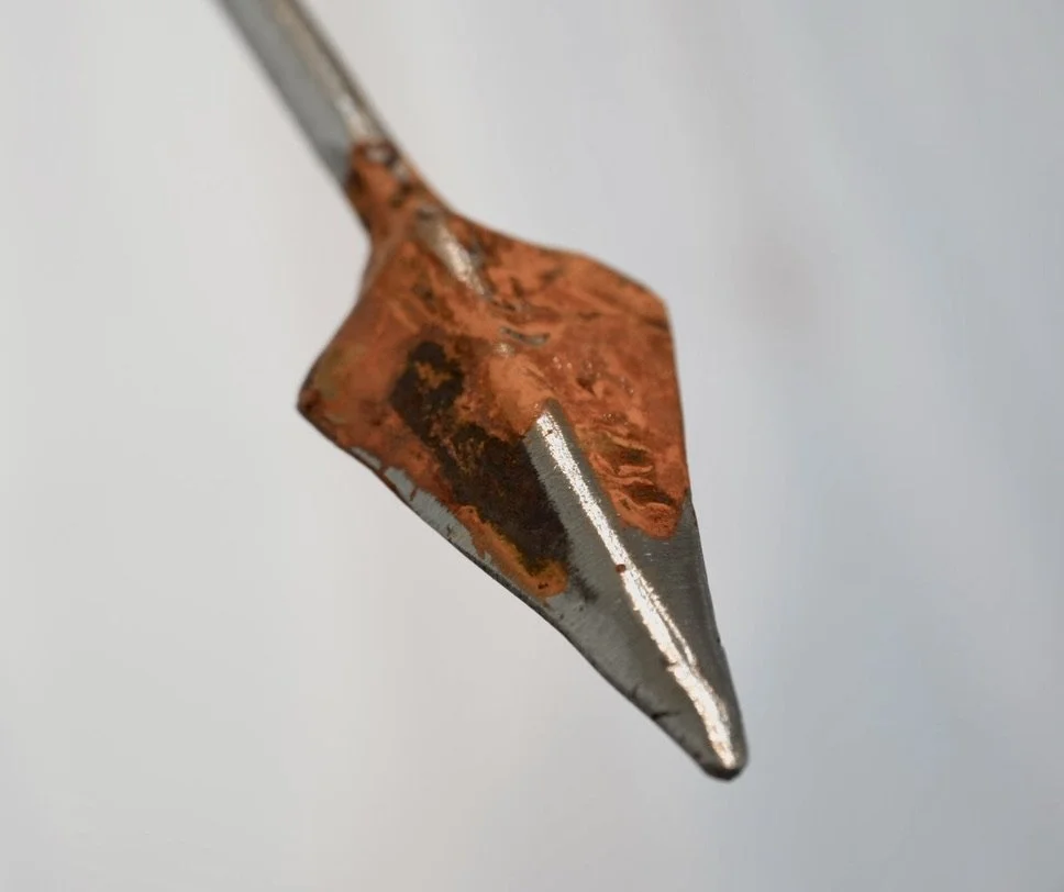 A detail image of a steel sculpture resembling a spear or arrowhead.