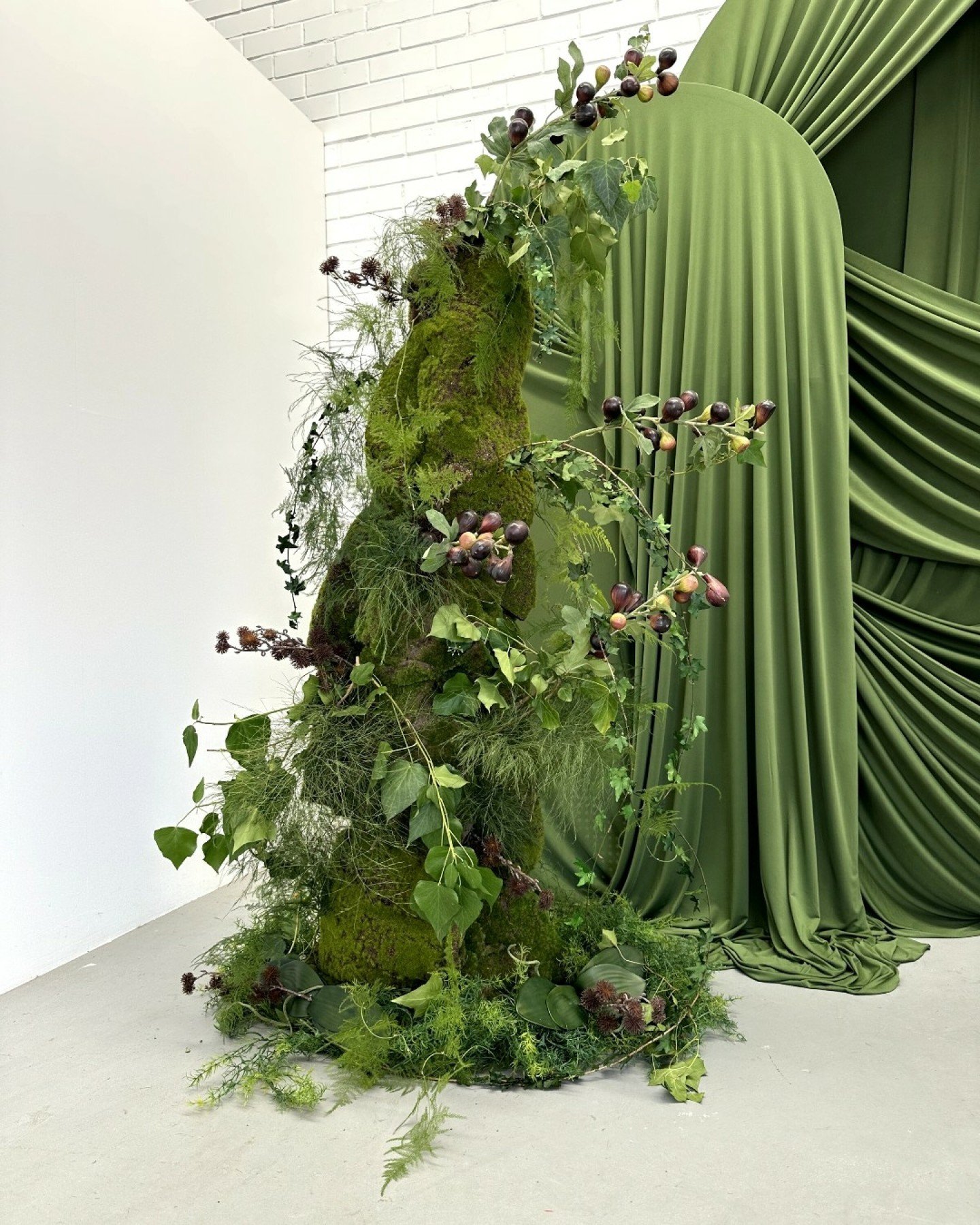 This whimsical botanical green display we created represents the 'eclectic editorial' trend perfectly. This style often mixes modern and vintage aesthetics with quirky additions, like the fig branches we've added to these moss towers. This style make