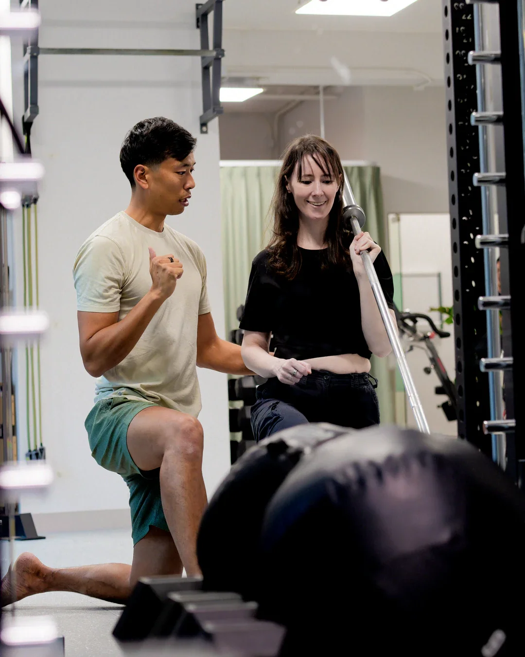 Male physiotherapist guiding a shoulder strength exercise to a female client