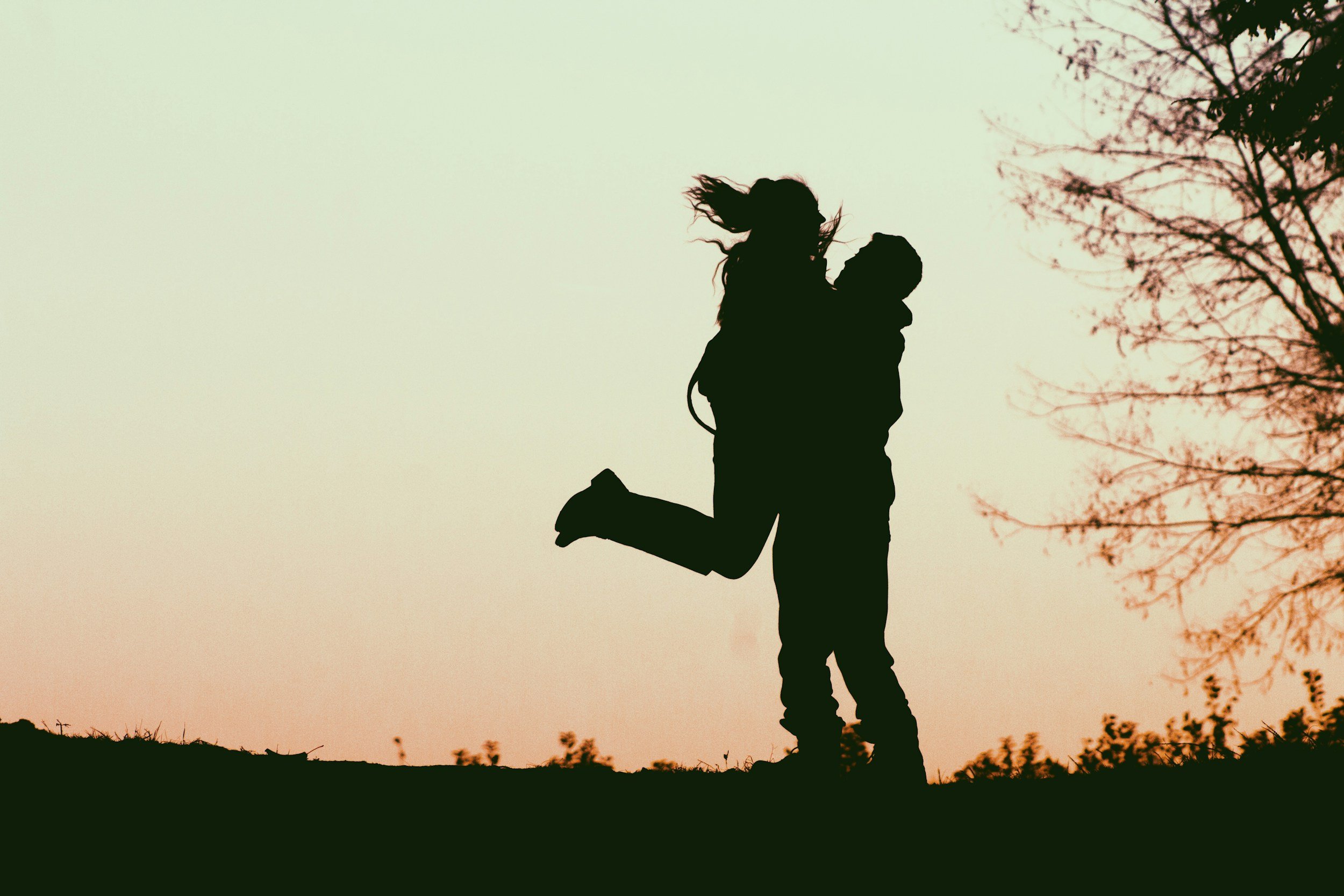 A couple embracing outdoors at sunset.