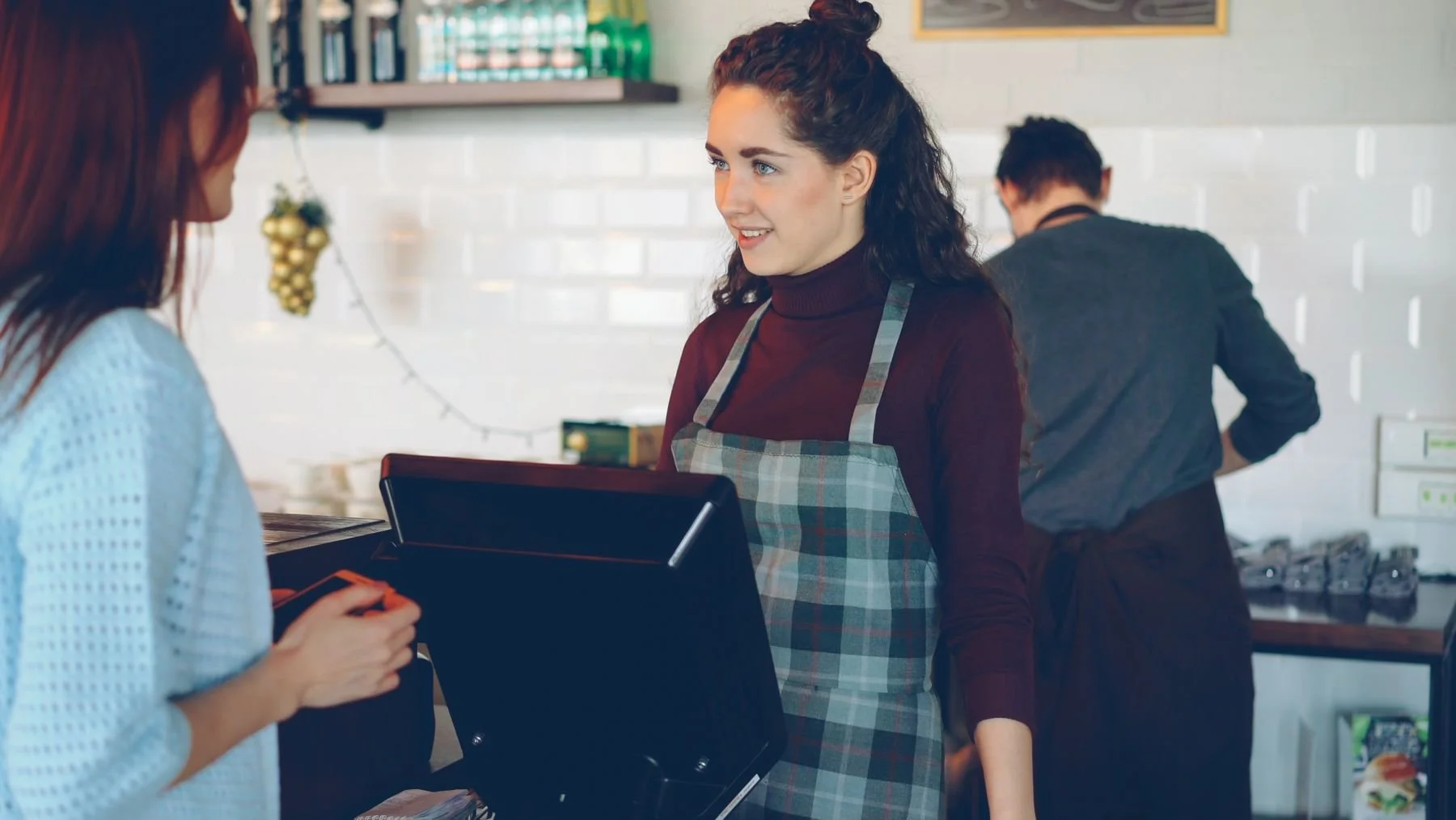 A café worker speaking with a customer at the counter.