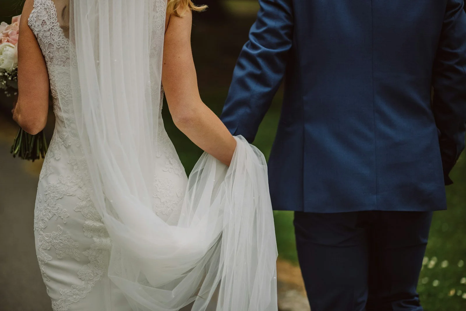 A newly married couple walking together, photographed from behind.