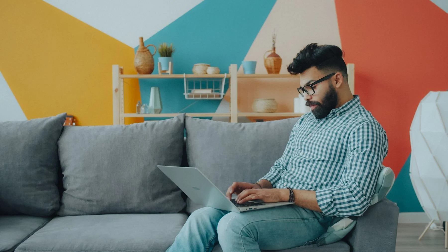 A person working on a laptop while seated on a sofa.
