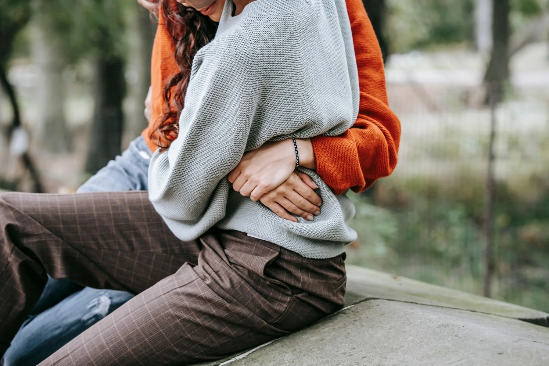 Two women embracing while seated outdoors.