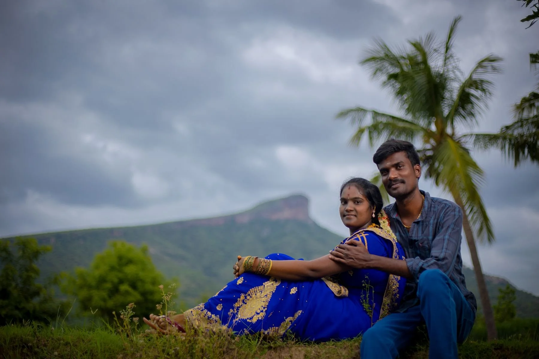 A South Asian couple in traditional clothing sitting together outdoors.