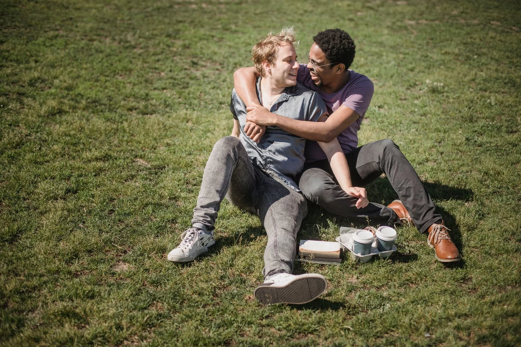 Two men sharing a relaxed picnic on the grass.