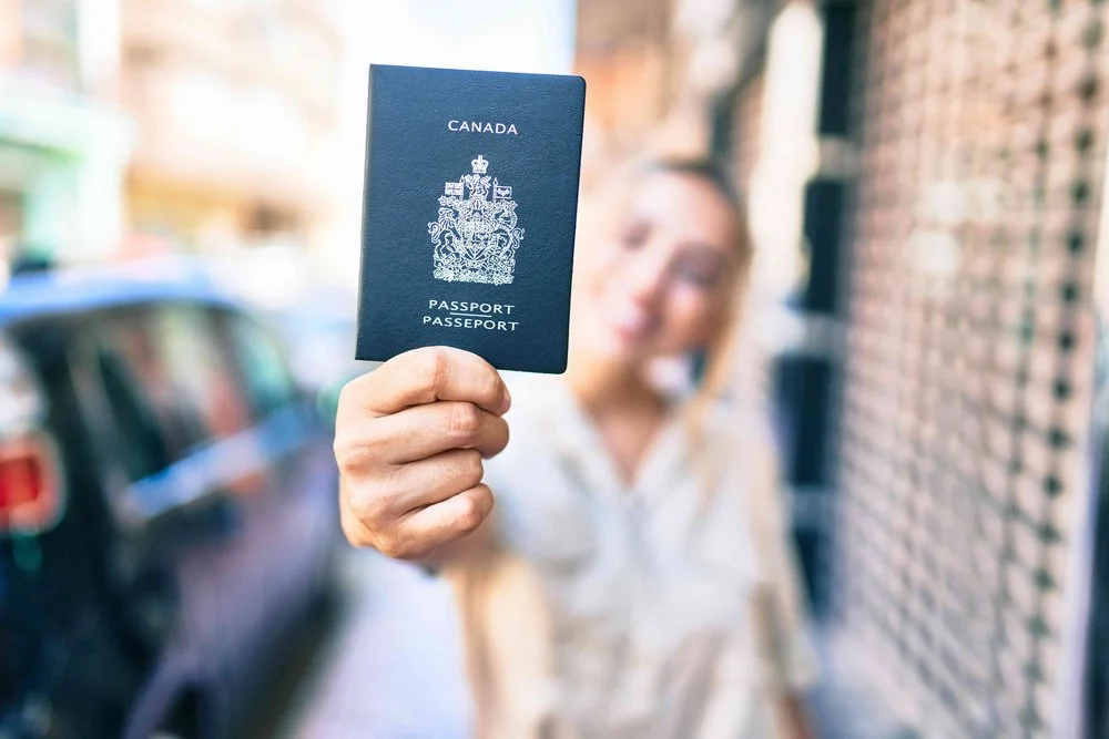 A person holding a Canadian passport outdoors.