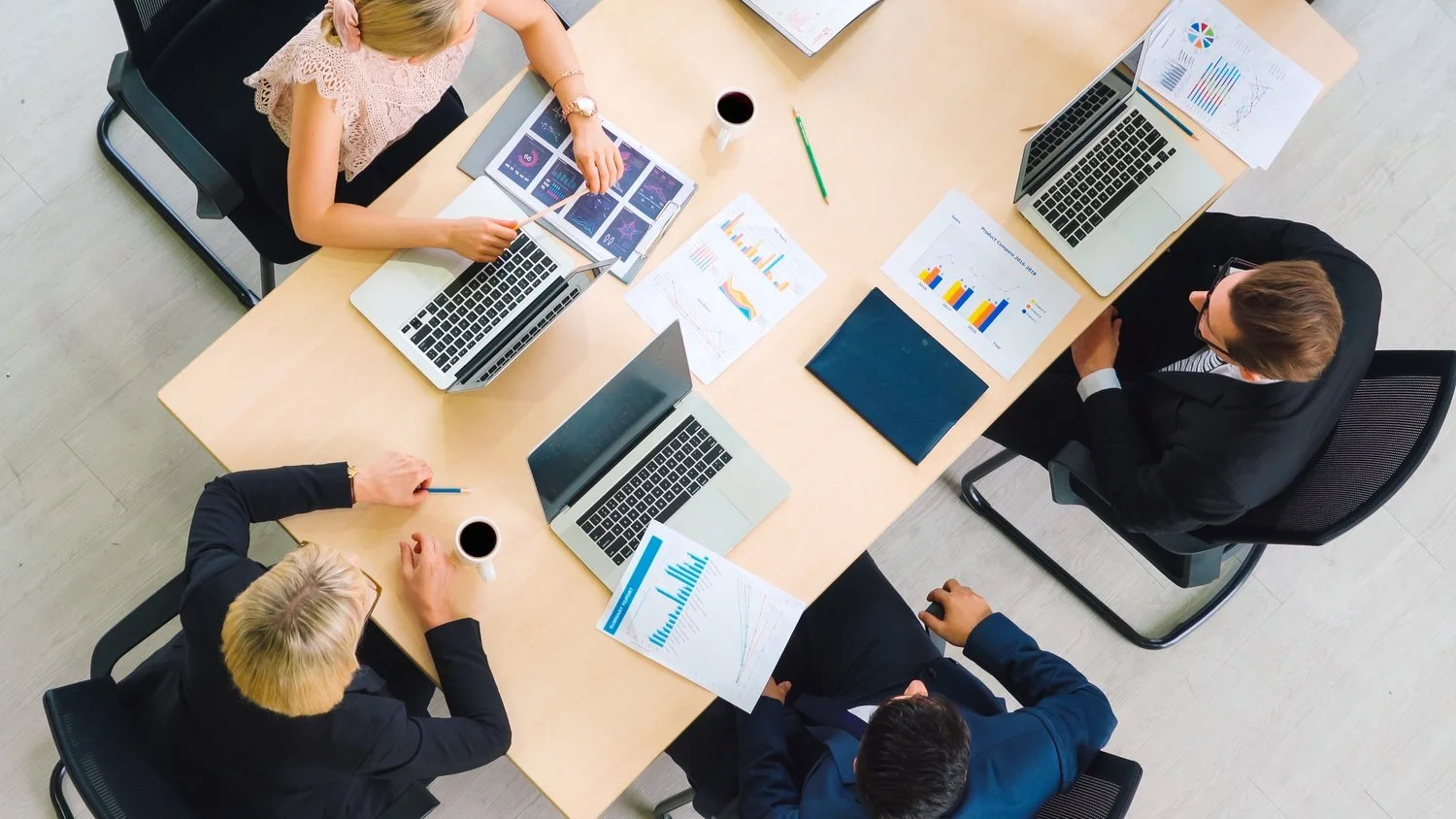 Office colleagues reviewing documents and charts around a table.