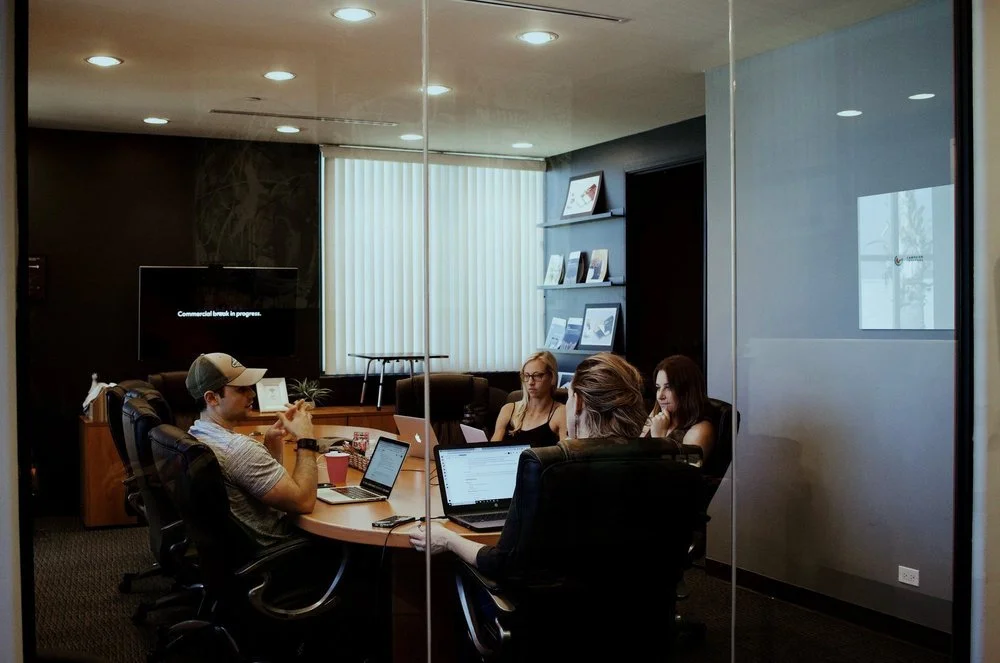 A group reviewing work on laptops in a meeting room.