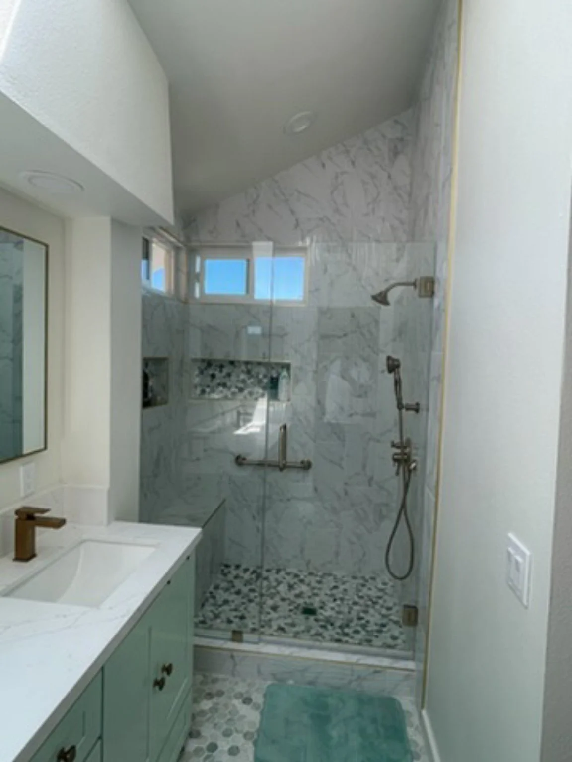 Completed residential bathroom remodel with a double vanity, glass walk-in shower, and patterned tile flooring