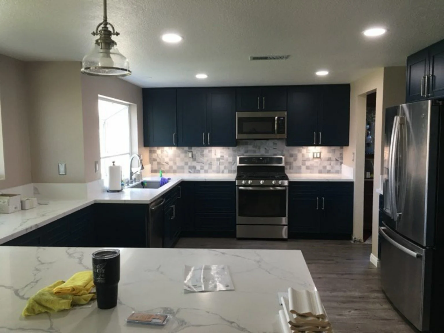 Completed kitchen with deep navy cabinetry, light stone counters and updated flooring