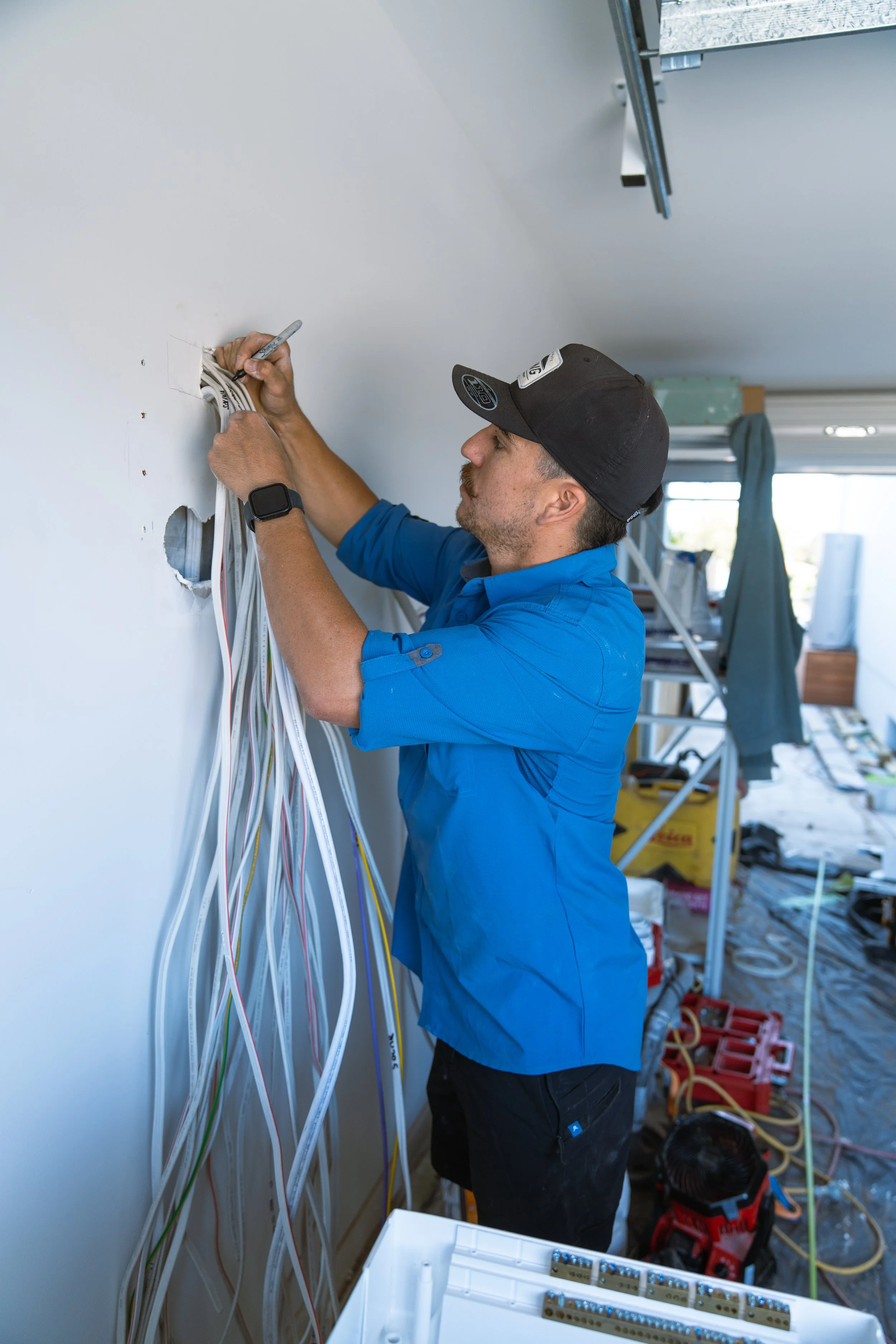A man installing or repairing electrical wiring inside a wall in a home renovation setting.