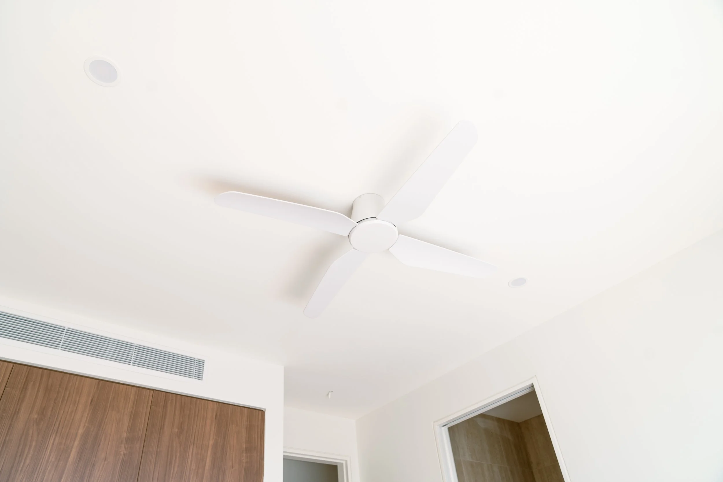 Ceiling fan with four blades mounted on a white ceiling in a modern room.