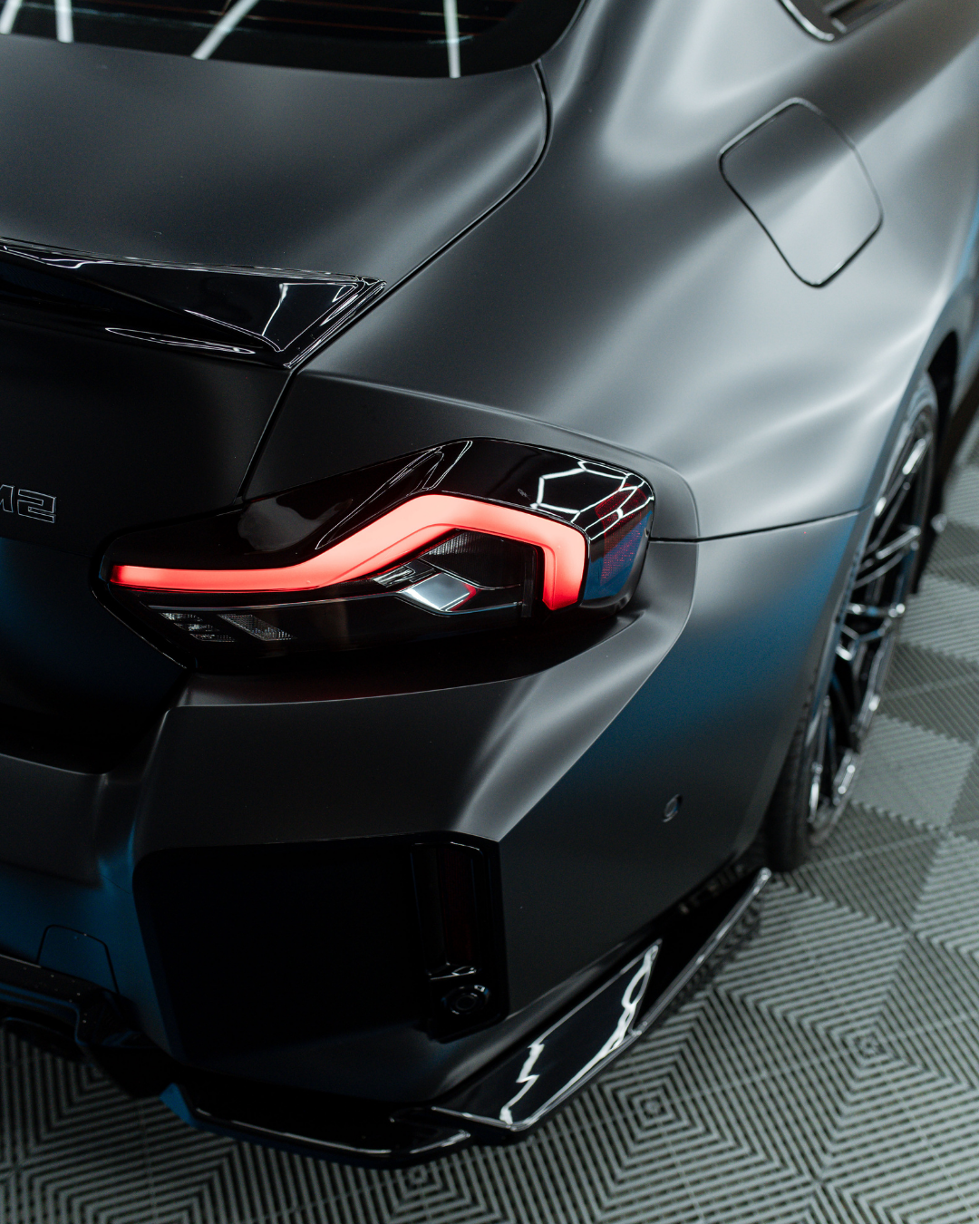 Close-up of the rear section of a black sports car, showcasing its sleek design, LED tail light, and matte finish.