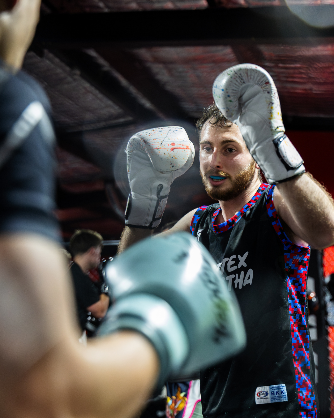A male boxer with boxing gloves, training in a gym.