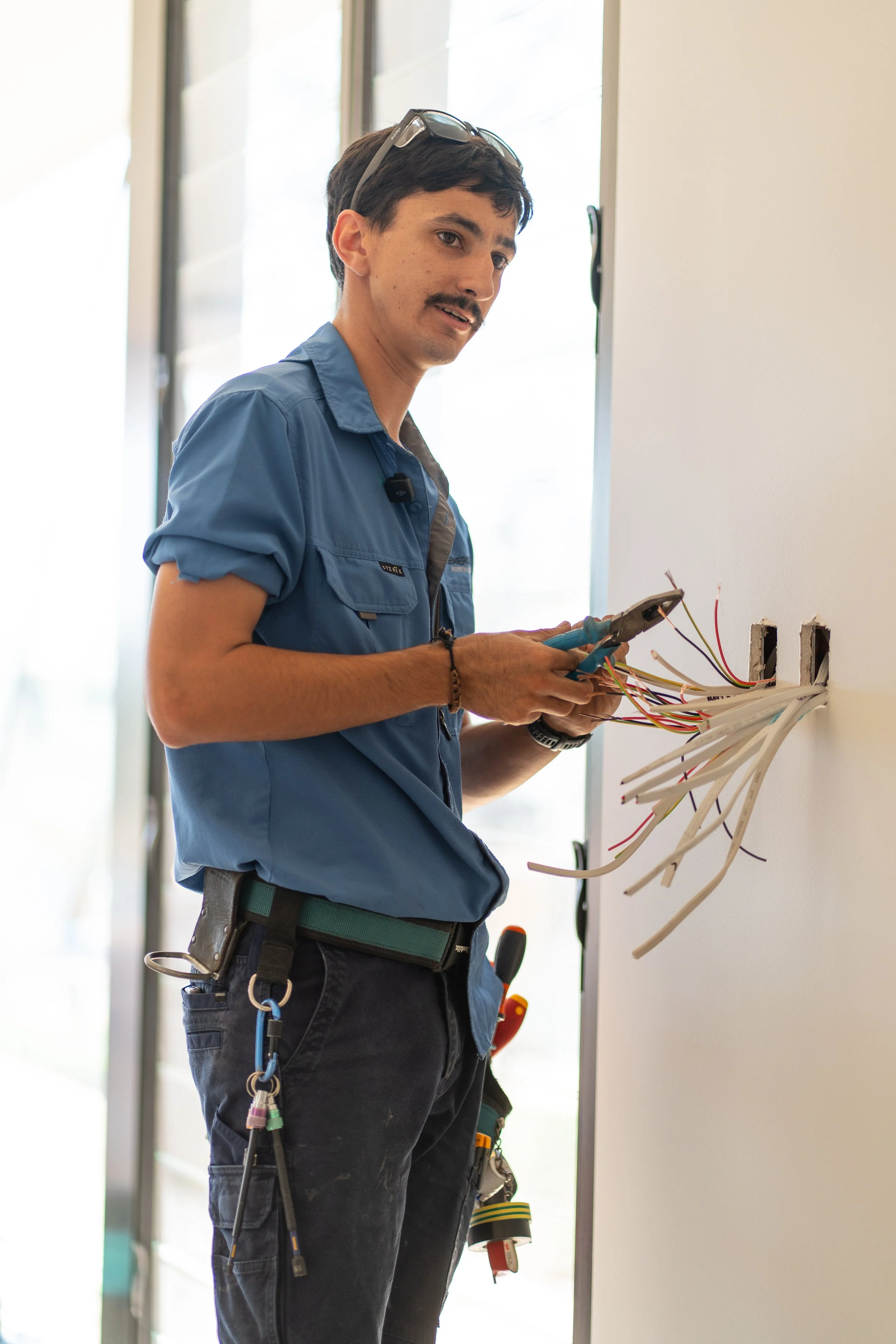 Electrician working on exposed wiring in a wall.