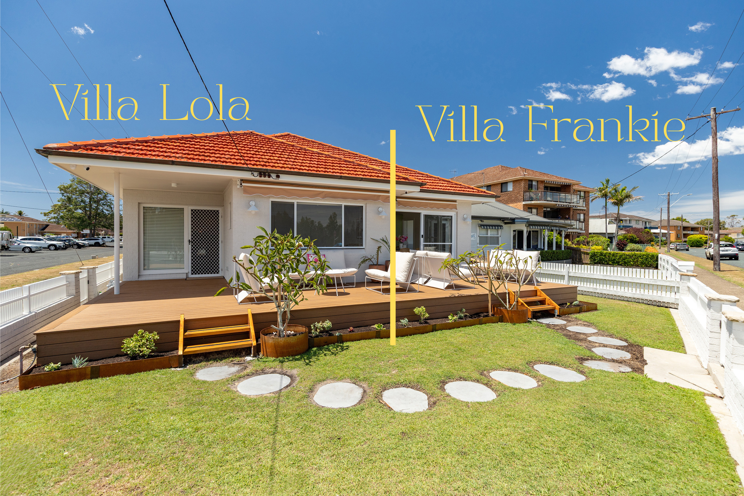 A side view of two adjacent houses with separate outdoor decks, labeled Villa Lola and Villa Frankie, under a clear blue sky with some clouds. The houses are separated by a thin yellow line.