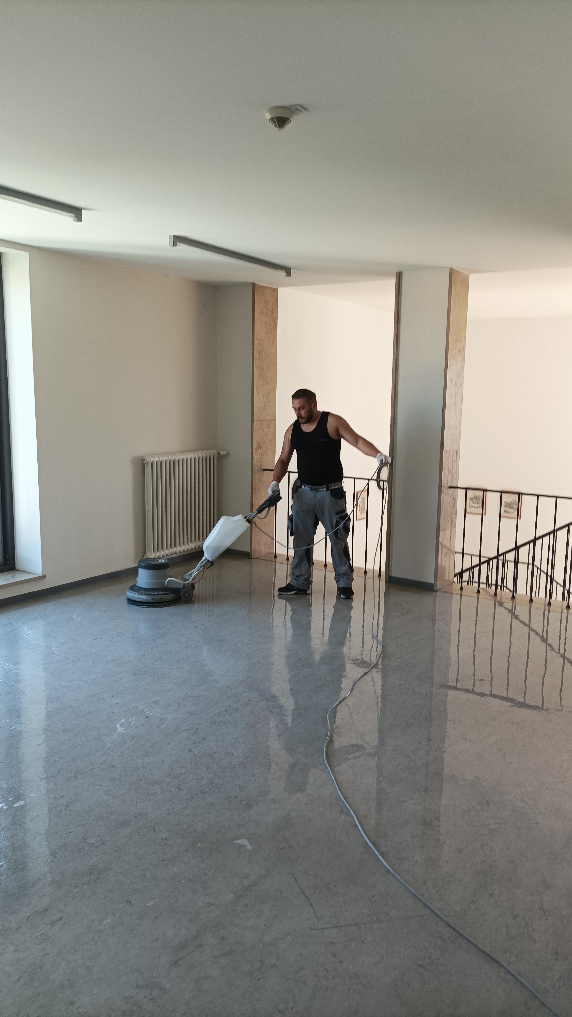Mann reinigt einen Boden mit einem Bodenwischer in einem Flur.