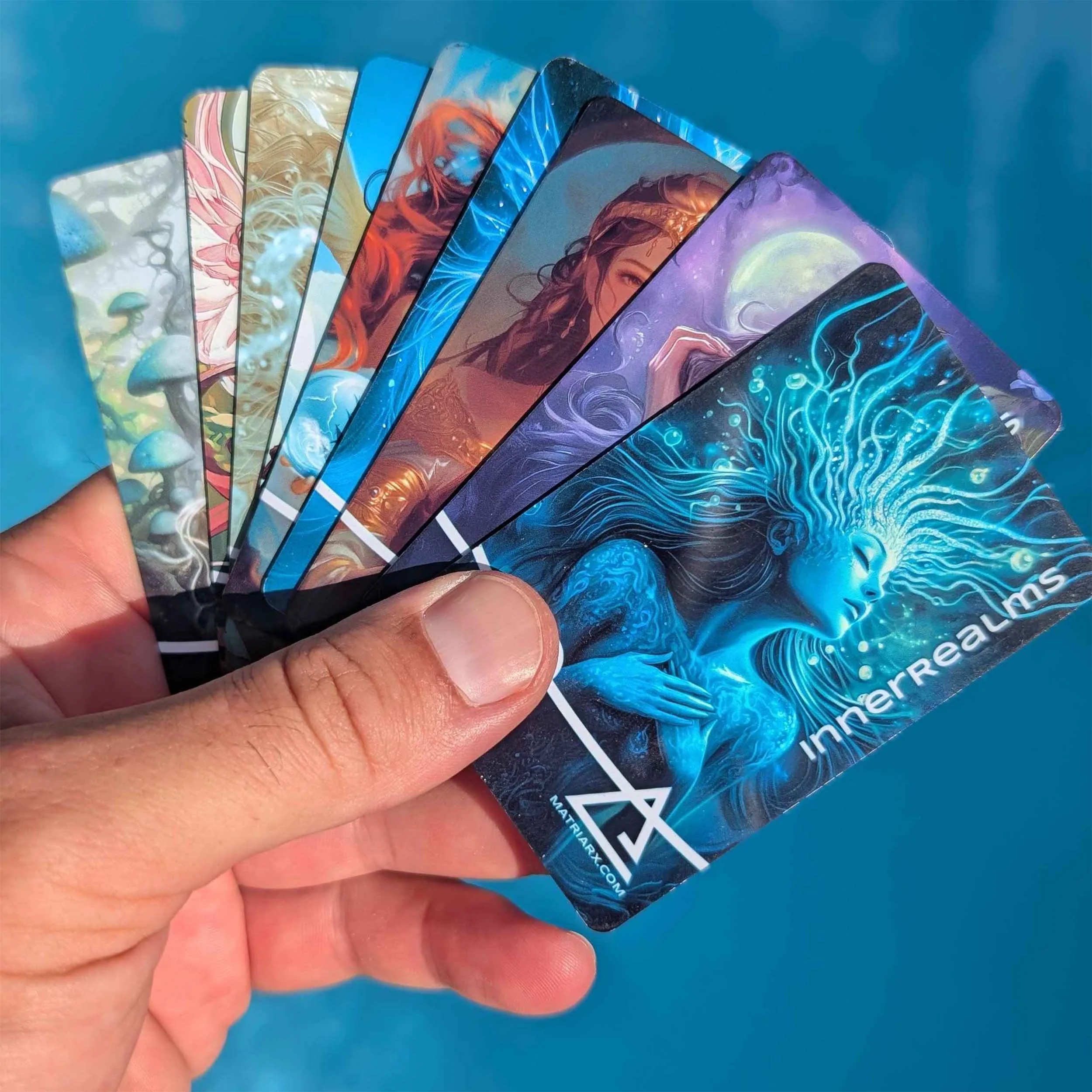 A hand holding several fantasy-themed trading cards fanned out against a blue background, featuring illustrations of mystical characters and creatures.