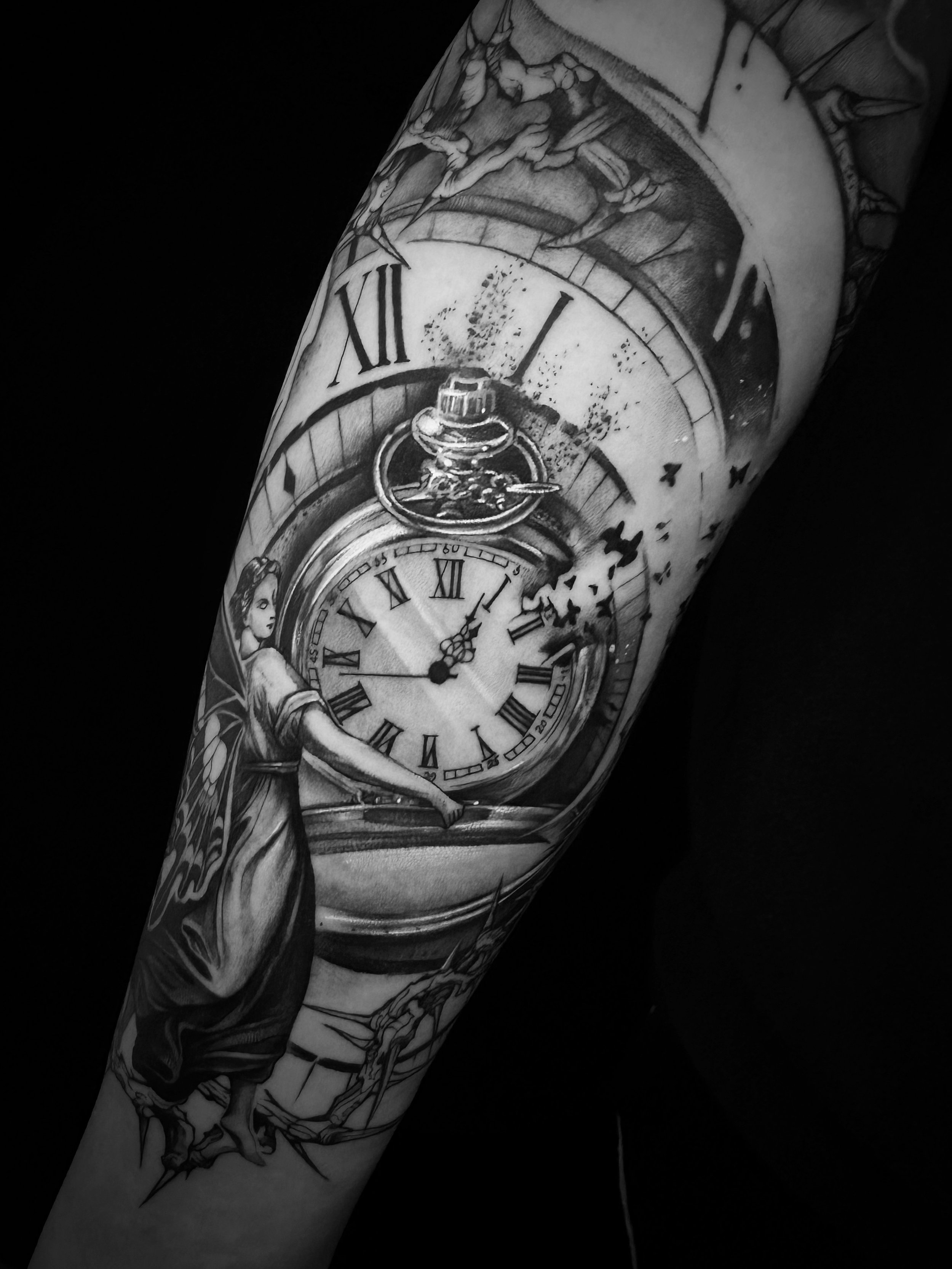 Black and white tattoo featuring a large pocket watch with Roman numerals, surrounding butterflies, and a woman with wings on an arm.