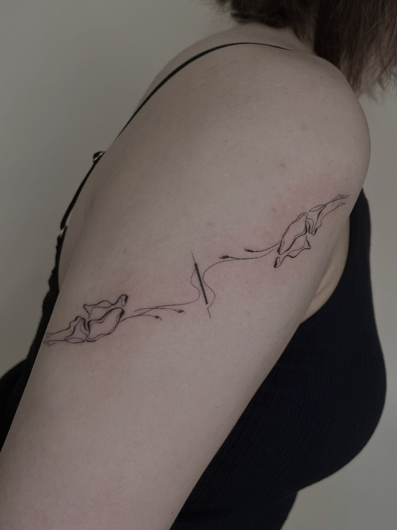 Minimalist floral line tattoo on upper arm