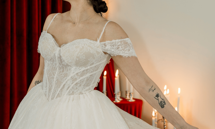 Bride wearing a vintage-inspired basque waist wedding dress with lace corset detailing and off-the-shoulder sleeves.