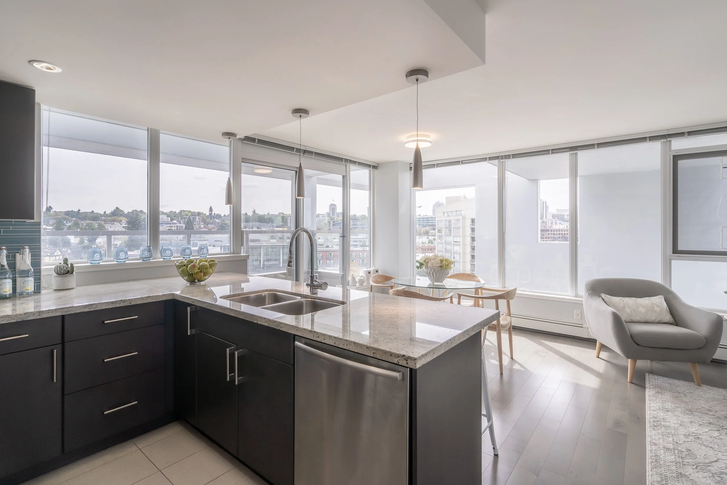 Modern kitchen with an island, granite countertops, stainless steel appliances, and large windows with city views.
