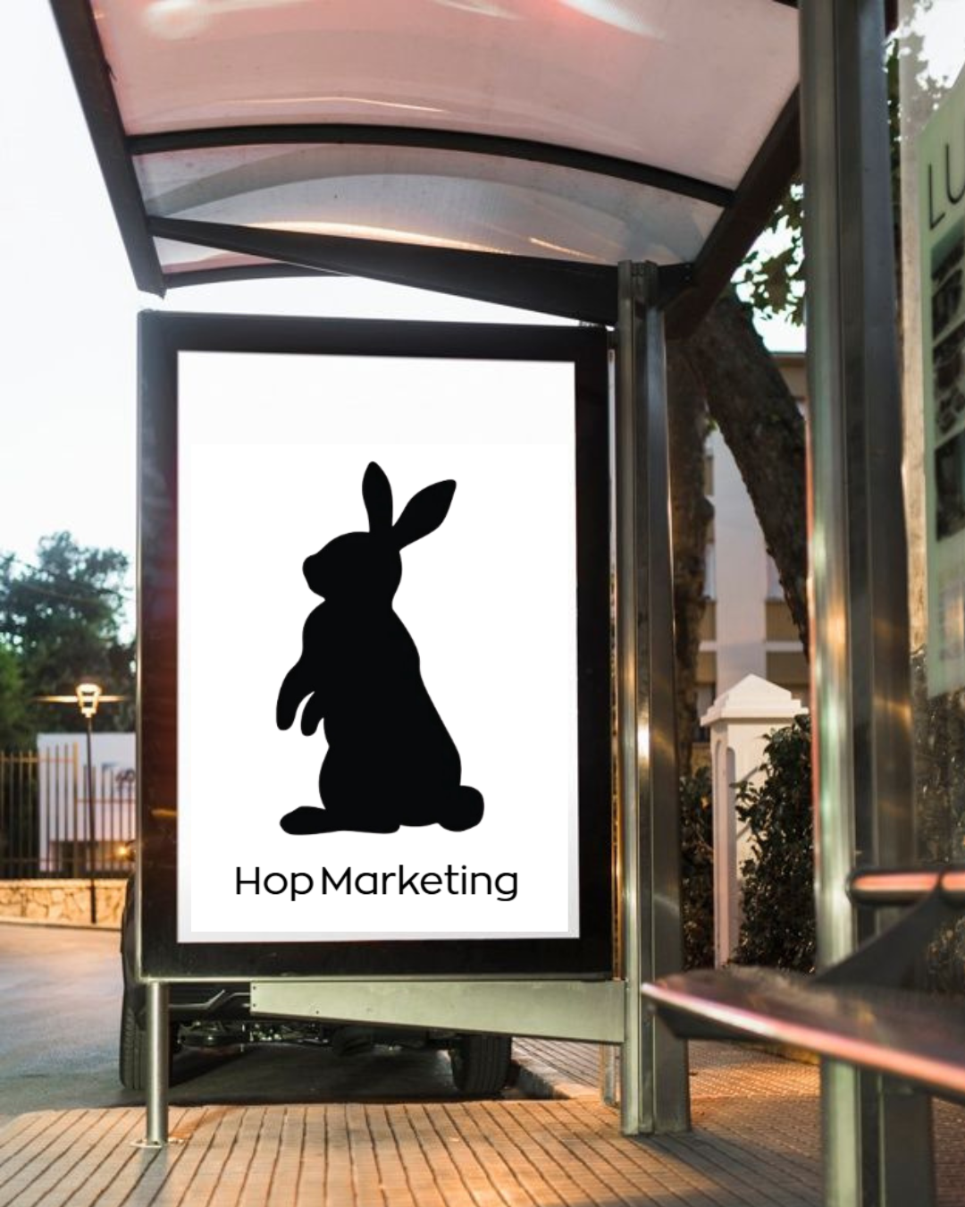 Publicidad en una parada de autobús con una silueta de conejo negro y el texto "Hop Marketing".