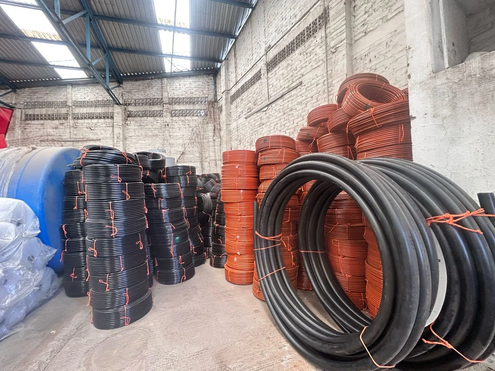 Rollo de tuberías de plástico negras y rojas en un almacén