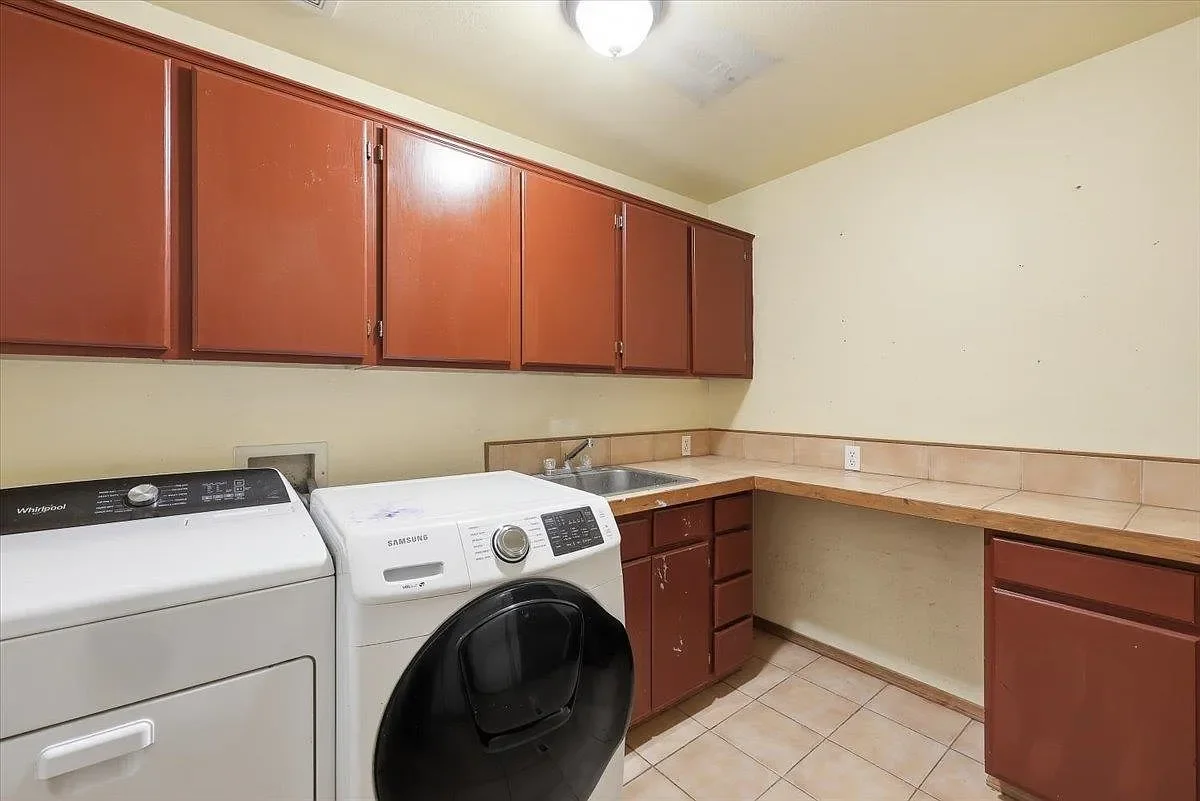 Laundry Room - Before. The original laundry room had dated cabinets, damaged tile floors, and a layout that left a ton to be desired. 