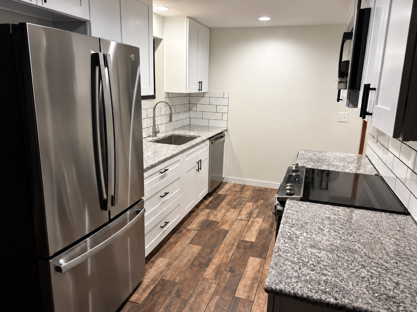 Kitchen - After. Complete with porcelain tile plank flooring, semi-custom cabinetry, granite countertops, new lighting, and subway tile backsplash. 