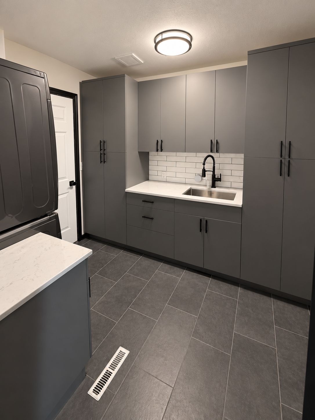 Laundry Room - After. We completely changed the layout and functionality of the laundry room, with new semi-custom cabinets, quartz counters and tile backsplash. We relocated the washer and dryer to the opposite wall making significantly better use o