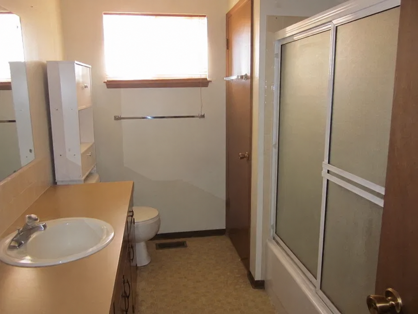Bathroom - Before. Featured the same outdated particle board cabinets and linoleum flooring as the kitchen. The outdated tub/shower had failing tile and grout joints leading to water getting behind the wall and creating the opportunity for thousands 