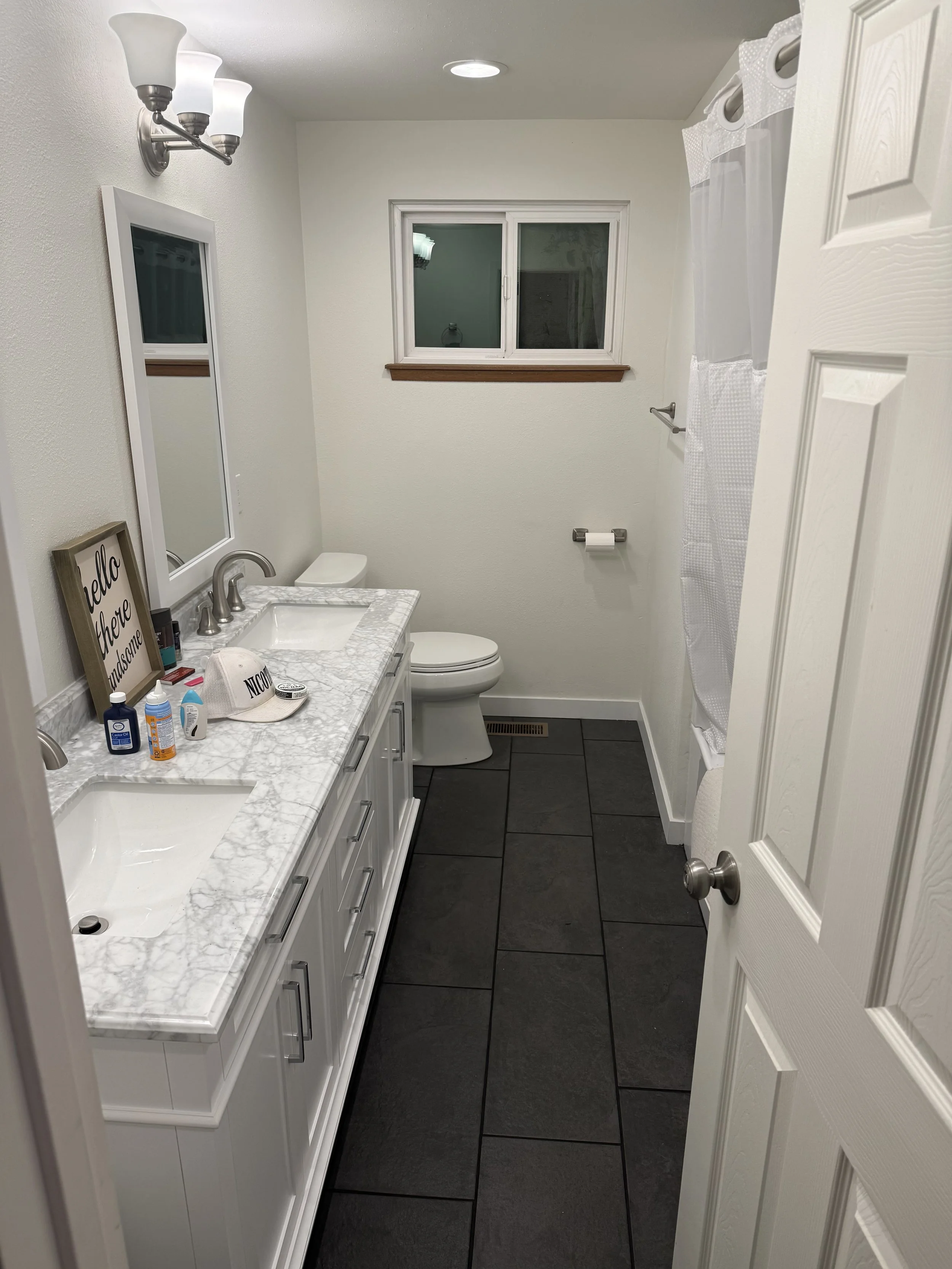 Kitchen - After. Featuring a new two-sink vanity with marble top, porcelain tile flooring, and a new tub/shower. The original bathroom also lacked an exhaust fan creating a massive opportunity for mold due to the poor ventilation so we added in a new