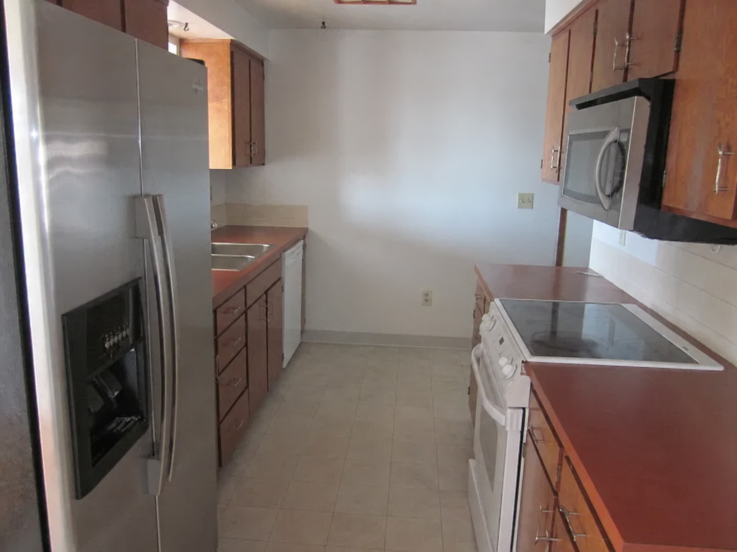 Kitchen - Before. Included linoleum flooring, particle board cabinets, and formica countertops, and a single fluorescent light fixture. 